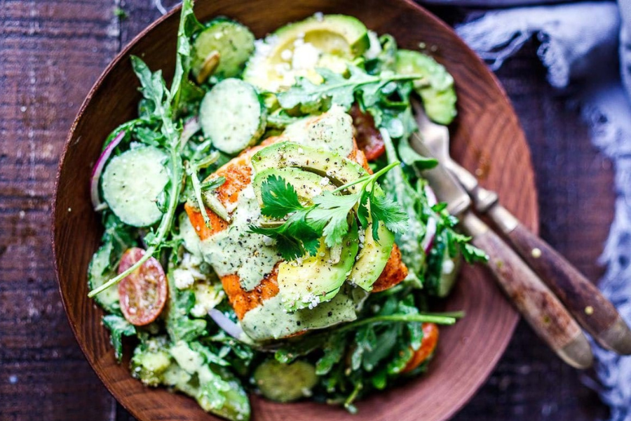 a mixed green salad with salmon and creamy cilantro dressing
