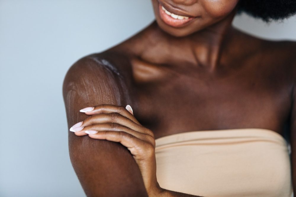 middle aged woman in perimenopause applying lotion to dry skin.