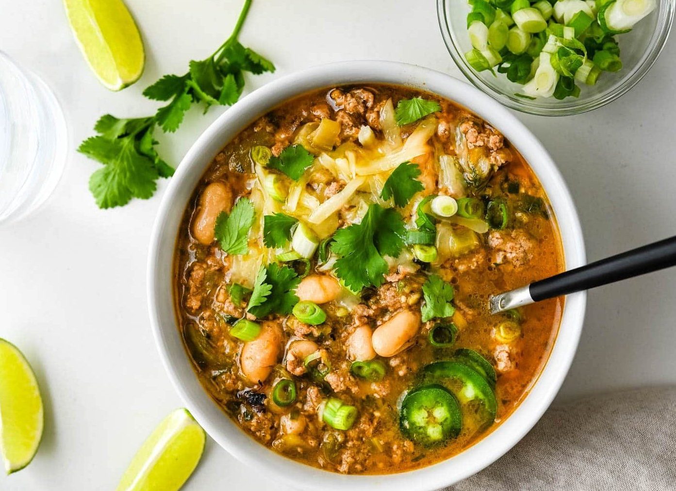 A warm bowl of healthy turkey white bean chili garnished with fresh green cilantro leaves.