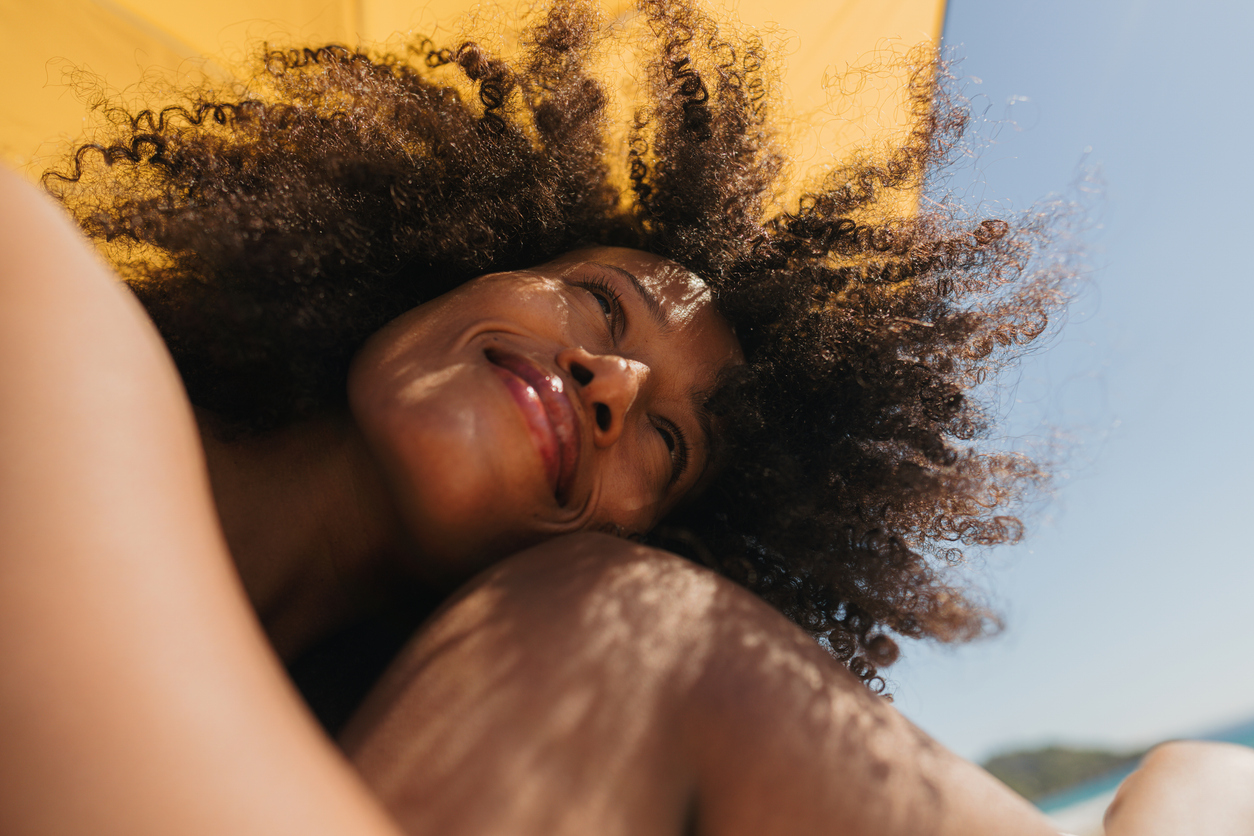 woman sunbathing wearing best anti-aging sunscreen for mature skin